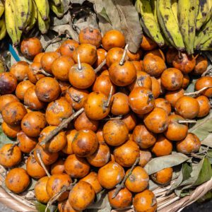 A basket of oranges and bananas on the ground.